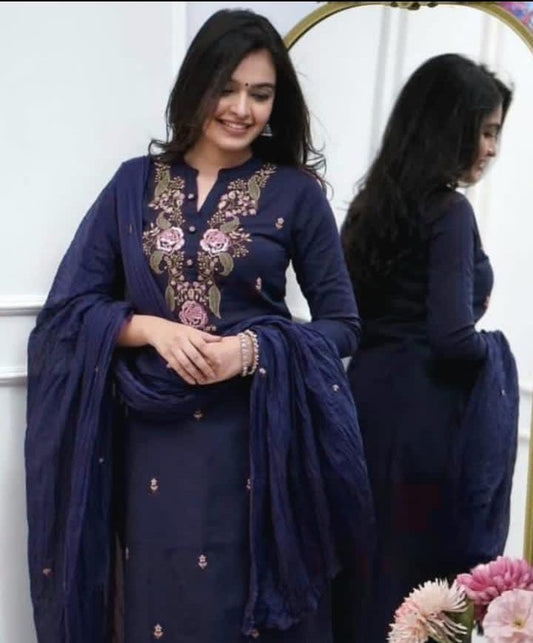 Woman in a navy blue embroidered outfit standing in front of a mirror.